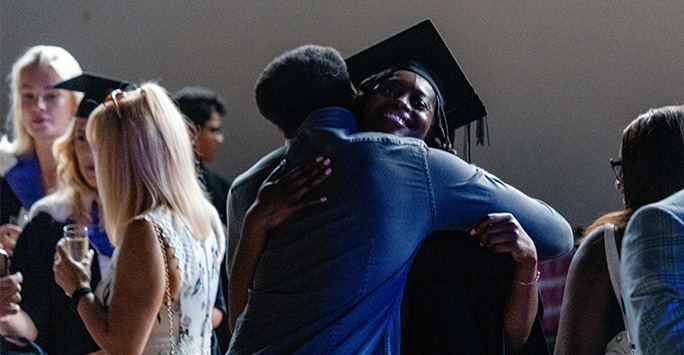 Graduate hugging a friend