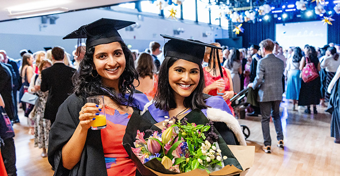 Graduates pose with bouquet of flowers
