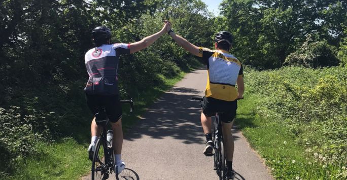 Two cyclists high five each other during their bike ride