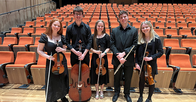 Five students pose in the Tung Auditorium with their instruments