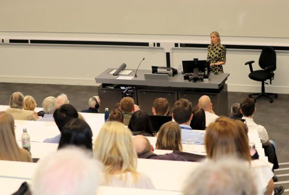Attendees sit in a lecture theatre watching Charlotte Hardman deliver a lecture