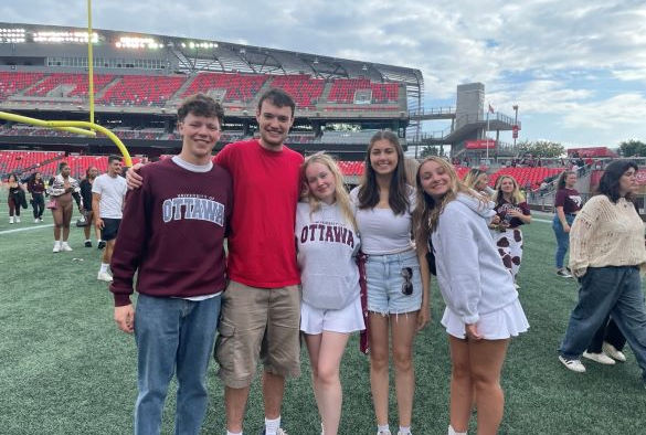 Students stand in a line in a football field