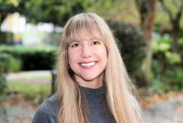 Dr Jenna Cummings stands in front of trees on campus