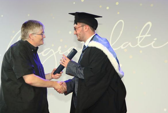 Professor Harrold shakes a student's hand and hands the student an award