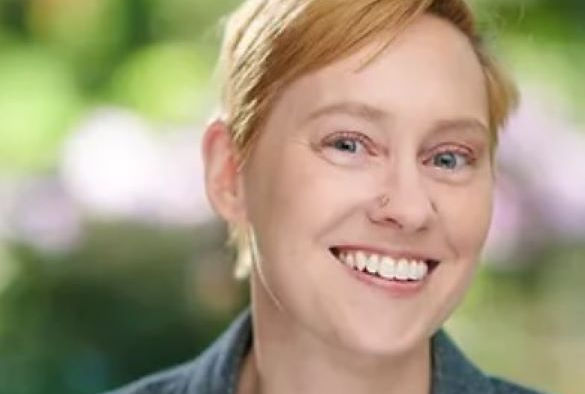 Dr Reshanne Reeder smiles and stands in front of trees