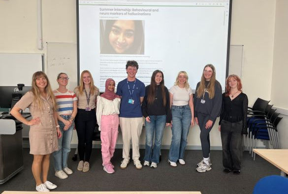 Students and supervisors stand in front of a projection screen