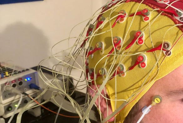 A participant wears a yellow and red EEG headset