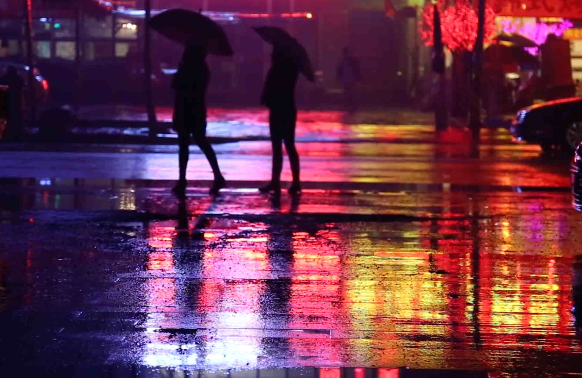 Two people standing in the rain at night