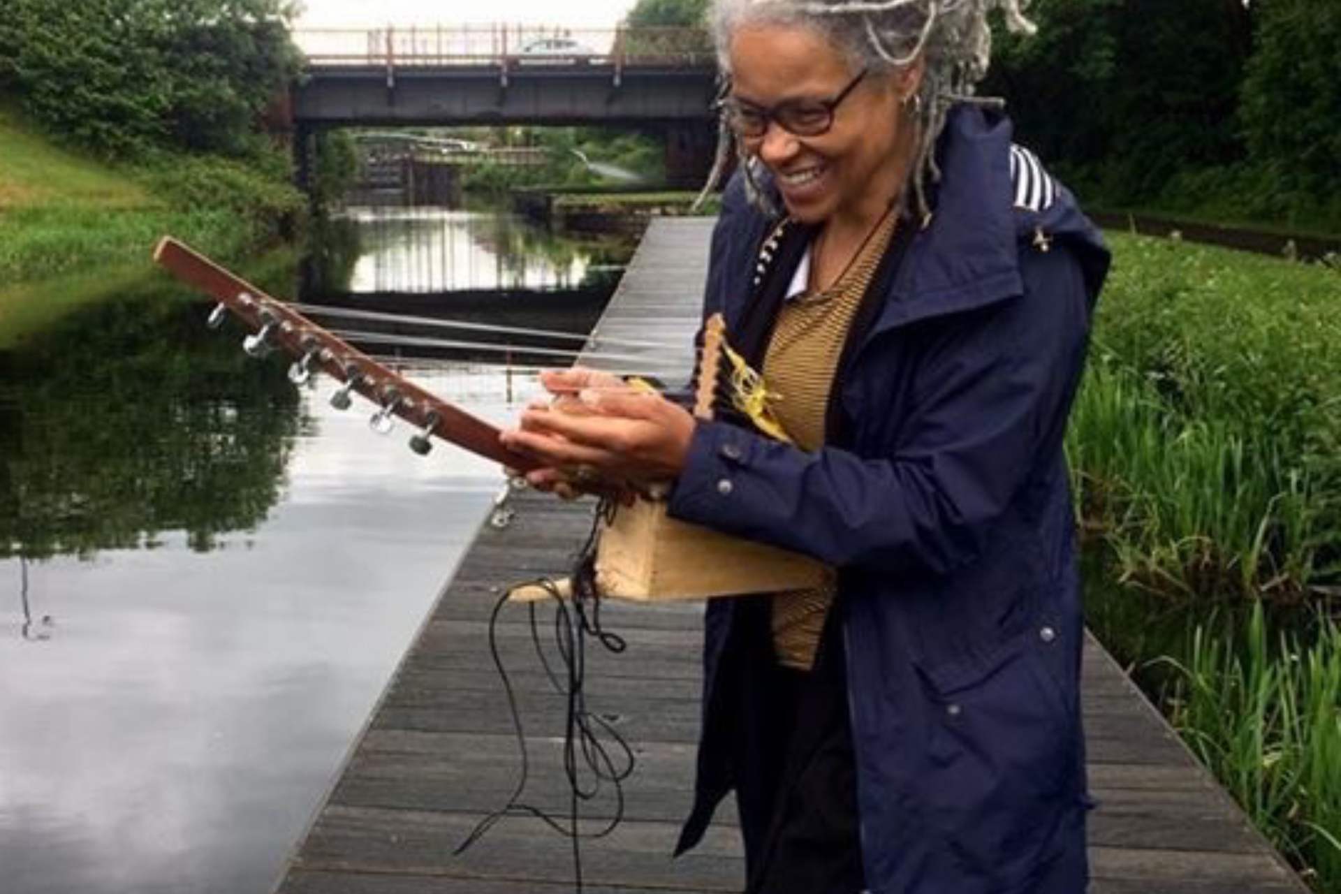 Woman playing stringed instrument by a canal