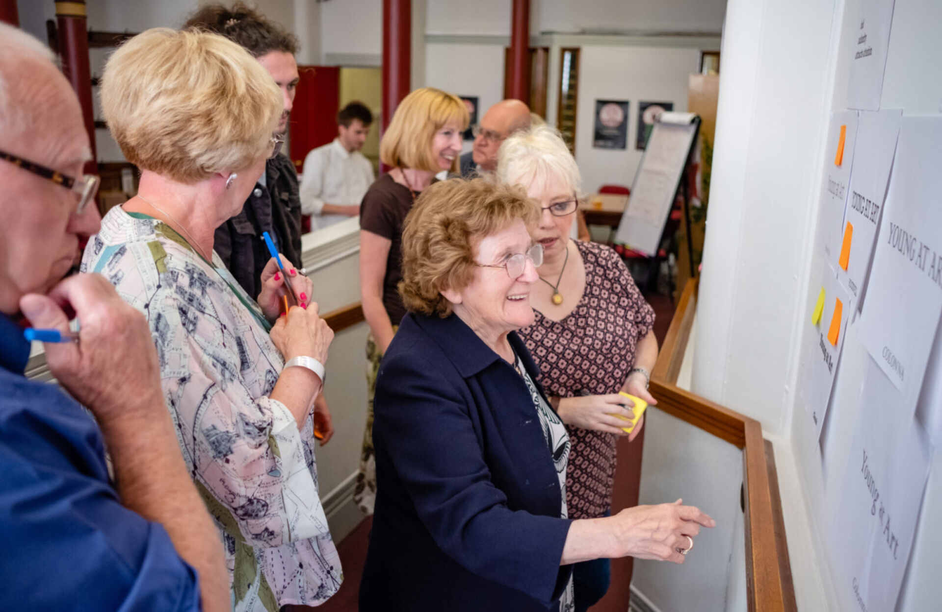 People looking at pieces of paper on a wall