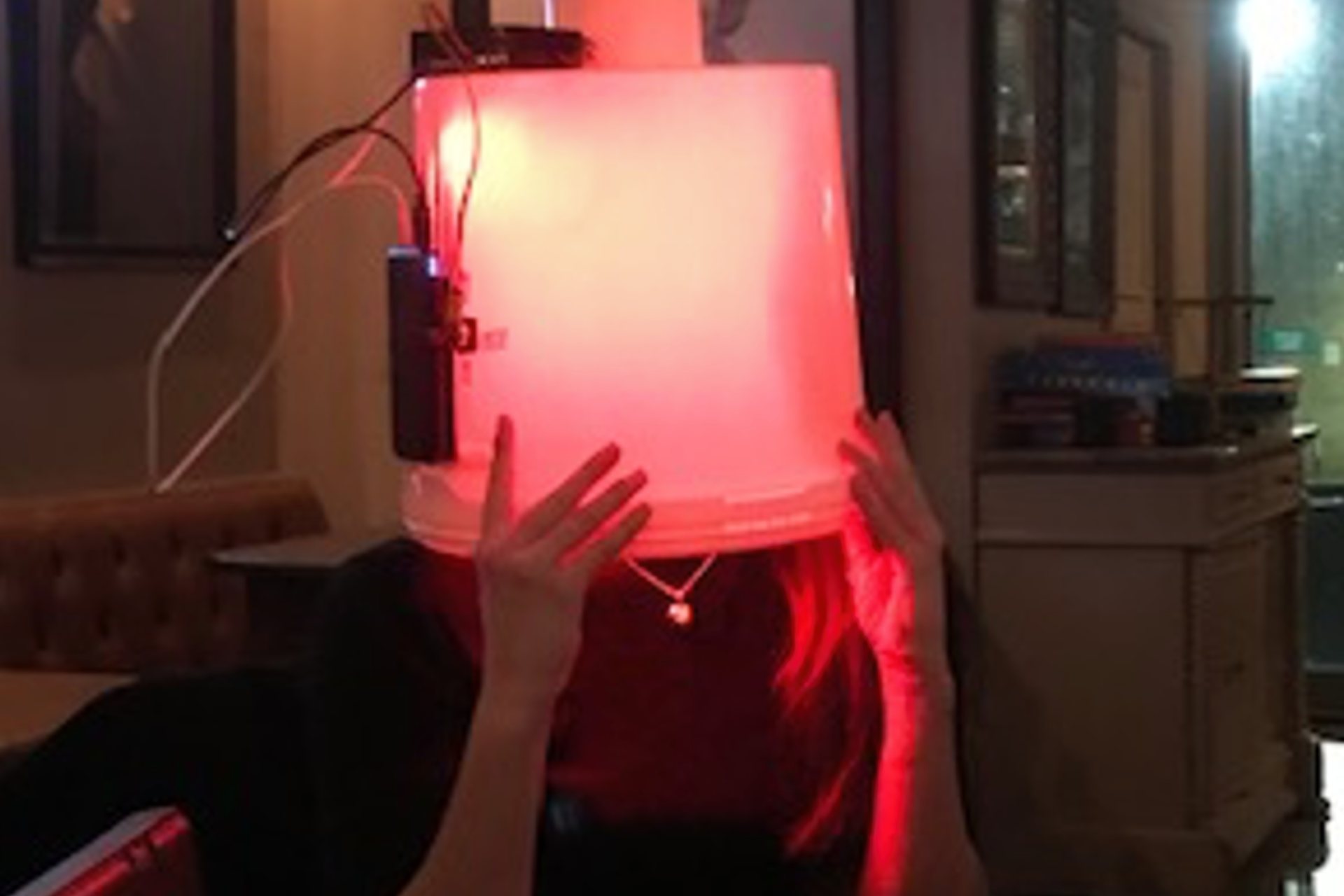 Person holding a red lamp in front of their face