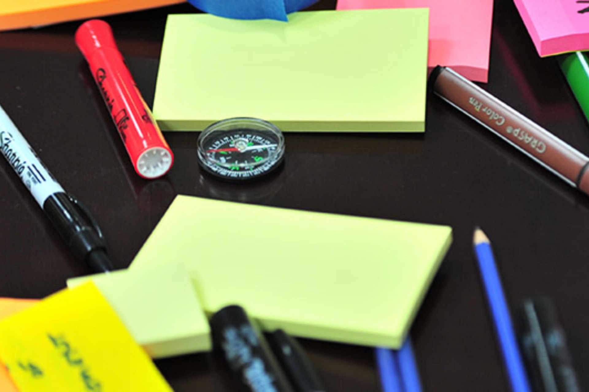 Photo of messy desk with pens and post-it notes