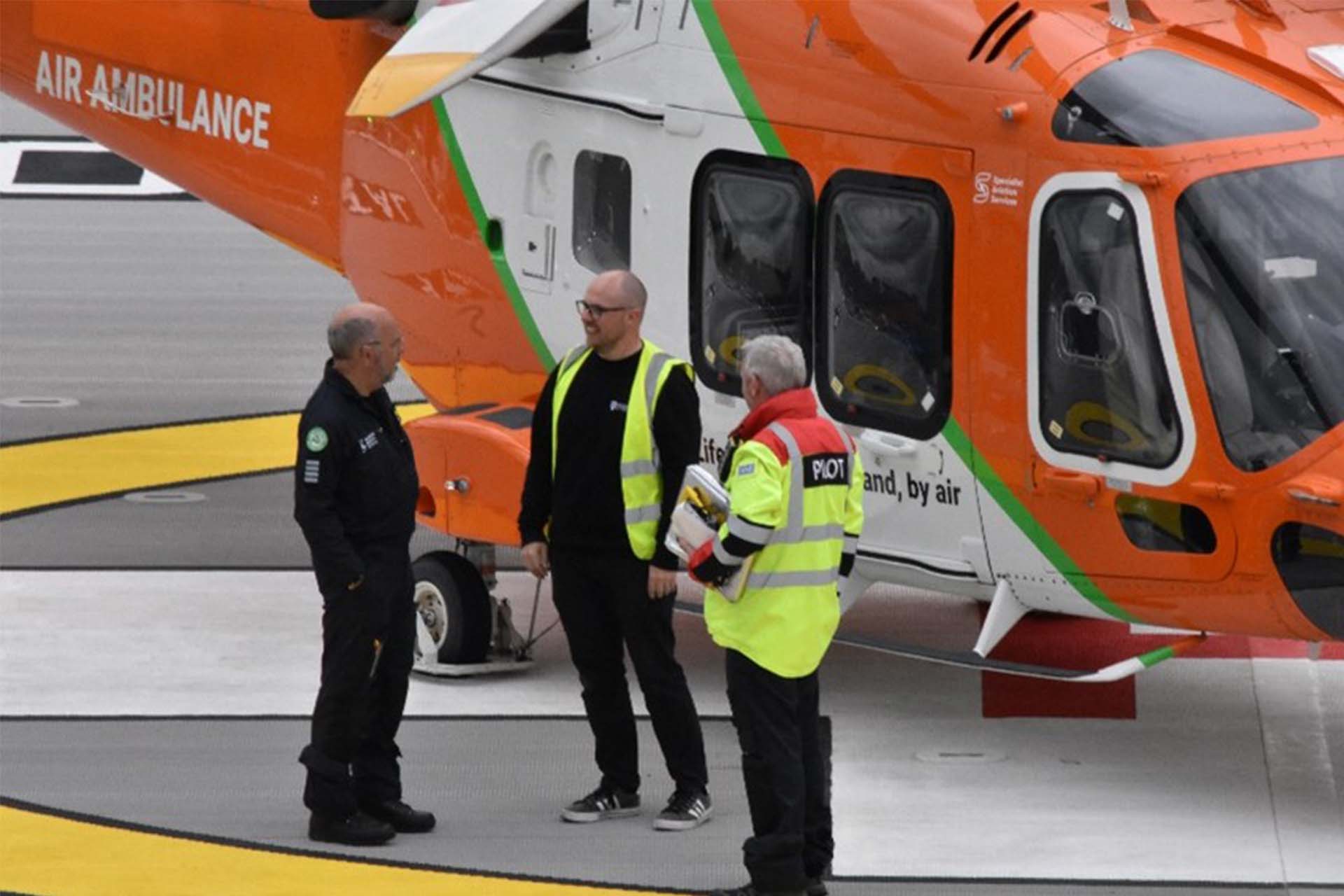 Dr Neale Watson meeting with colleagues near an air ambulance helicopter