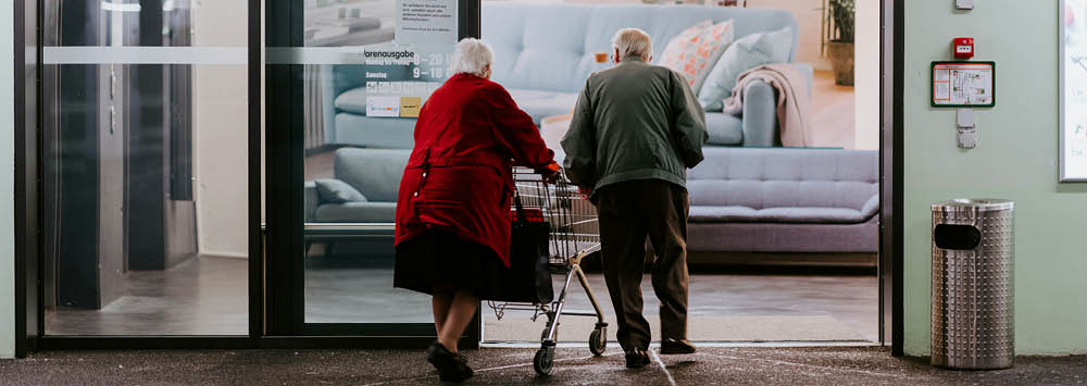 Two older people shopping with a trolley.
