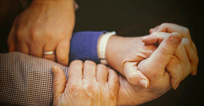 Older people holding hands.
