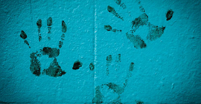 Black handprints on blue wall