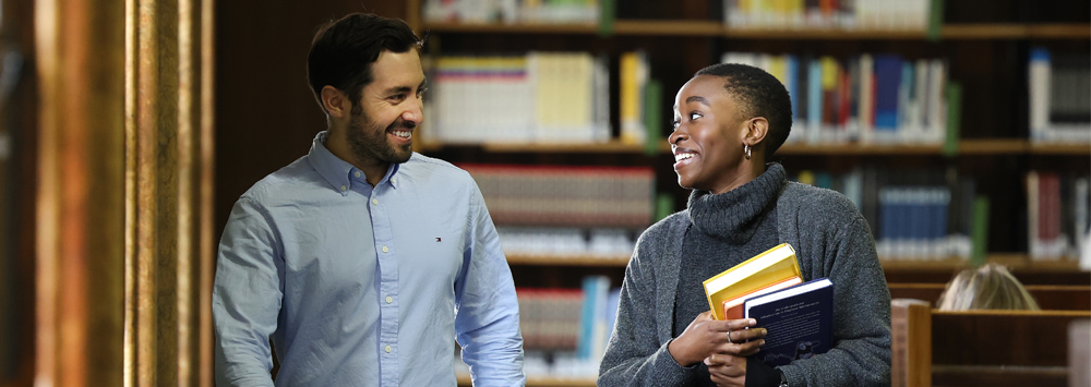 Two students waking through a library together.