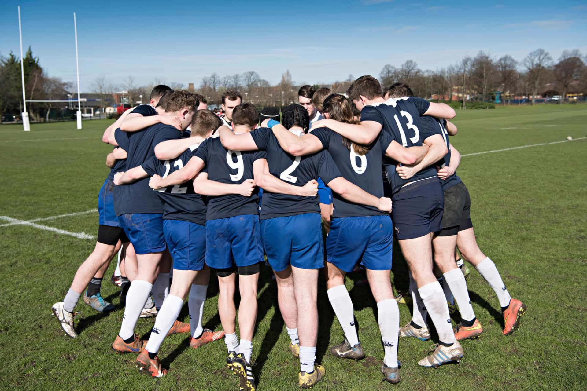 Sports team in a huddle on an outdoor pitch