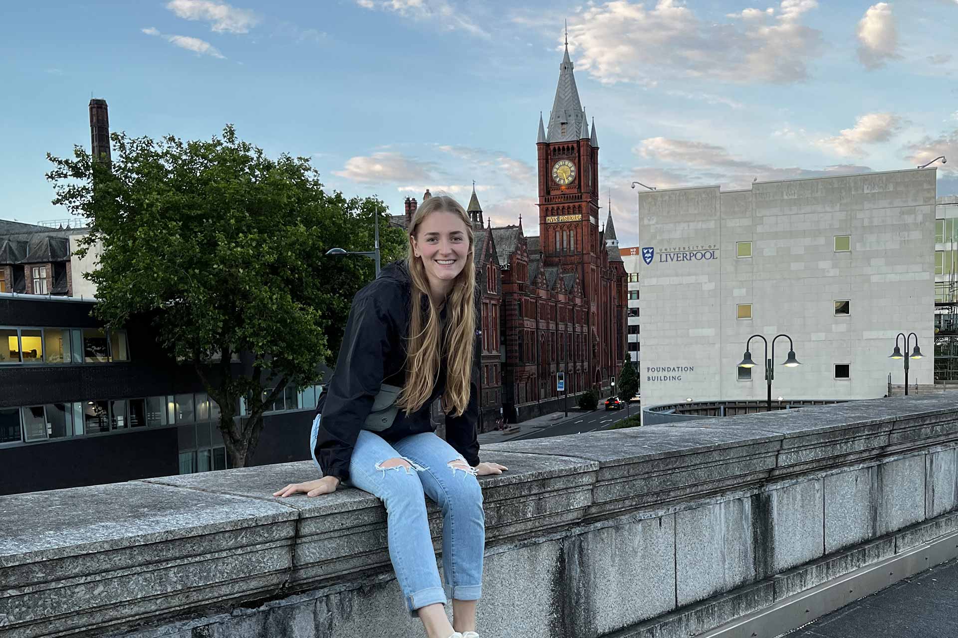 An International summer School student poses on a rooftop in front of the Victoria Gallery and Museum