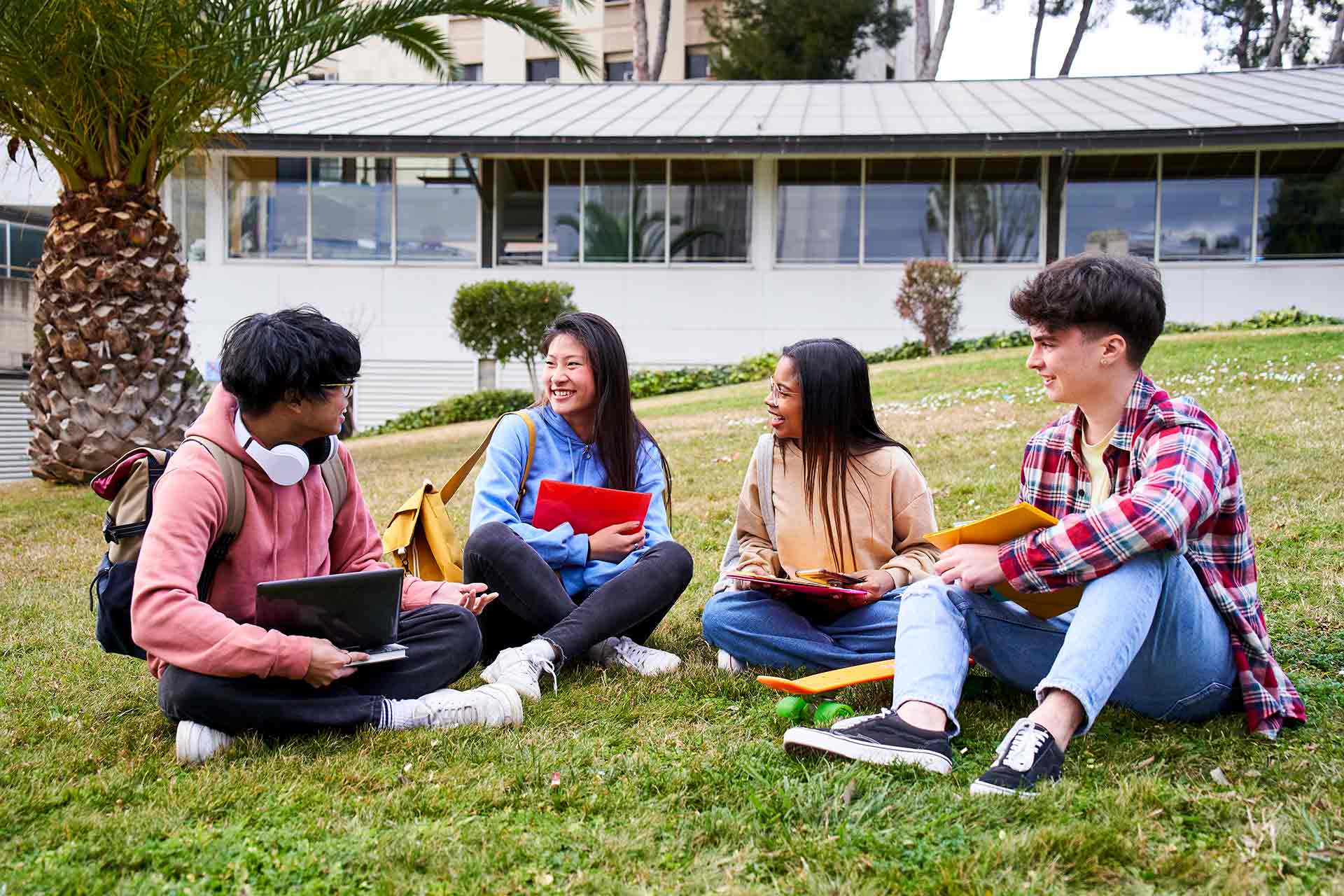 Four students sat on grass in an overseas college or university campus.