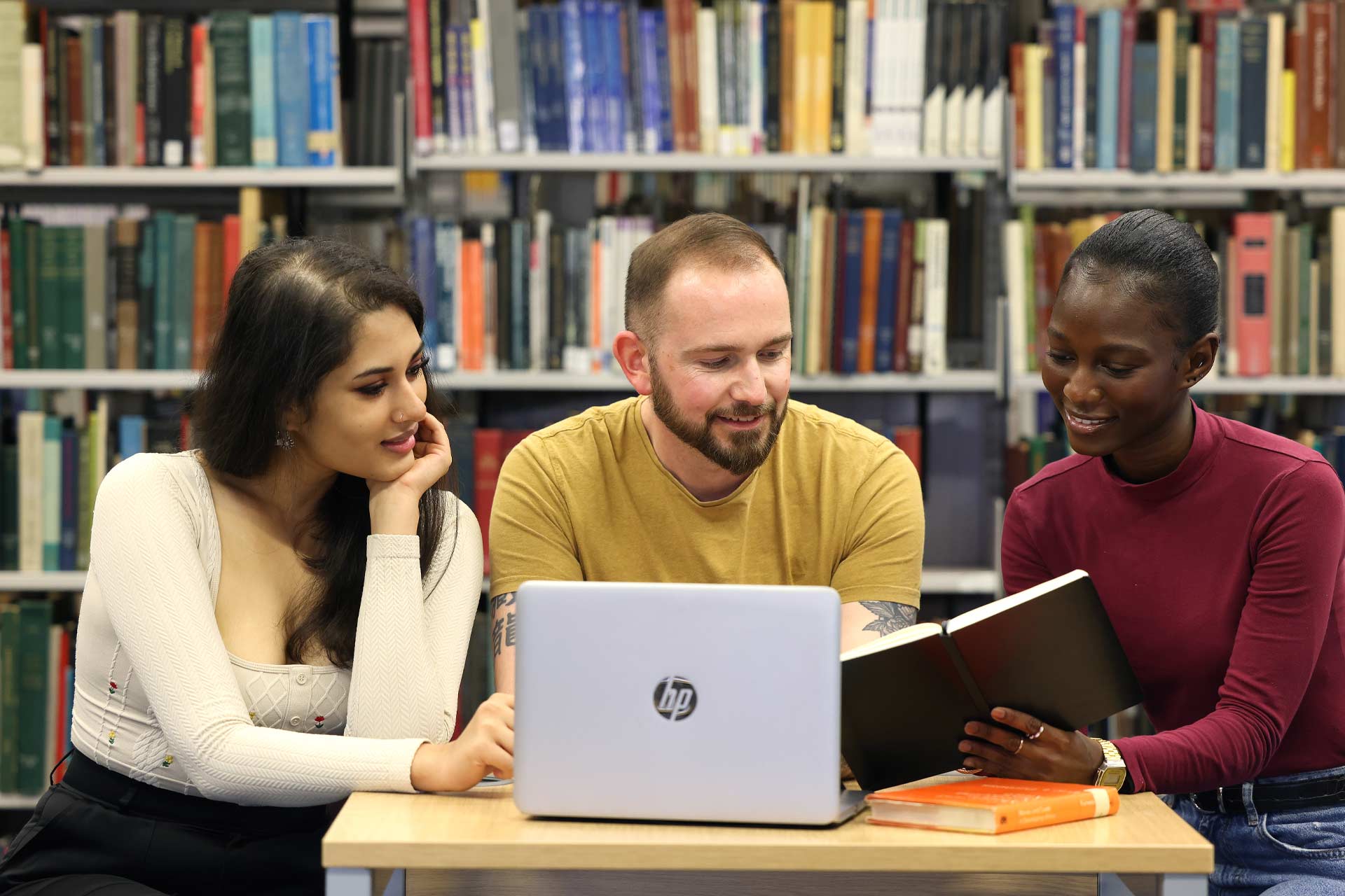 Anukriti Bisht, Lee Wainwright and Namonda Muyunda at a laptop in the library