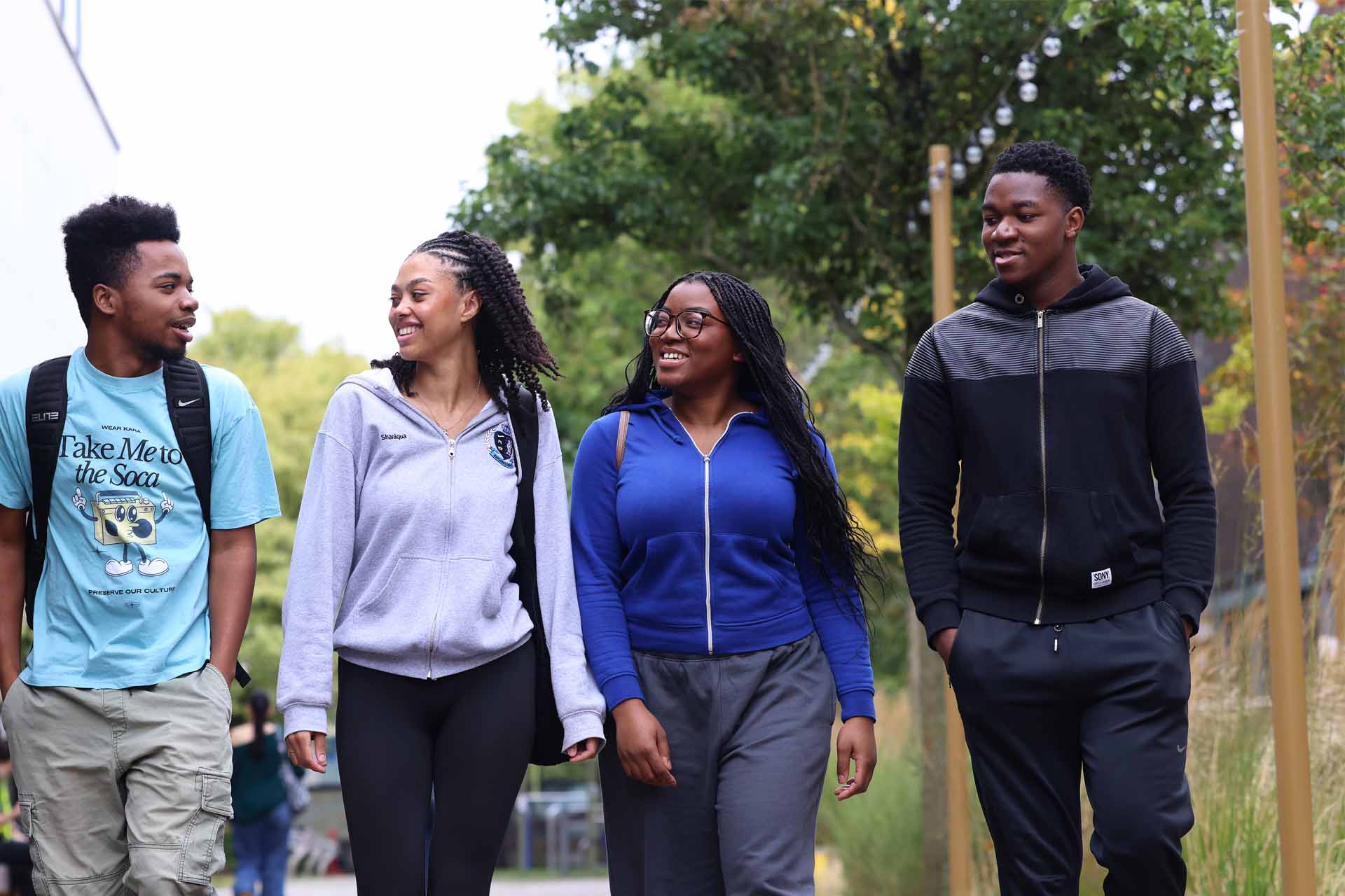 A group of four students are walking by the Liverpool Guild of Students, talking and smiling.