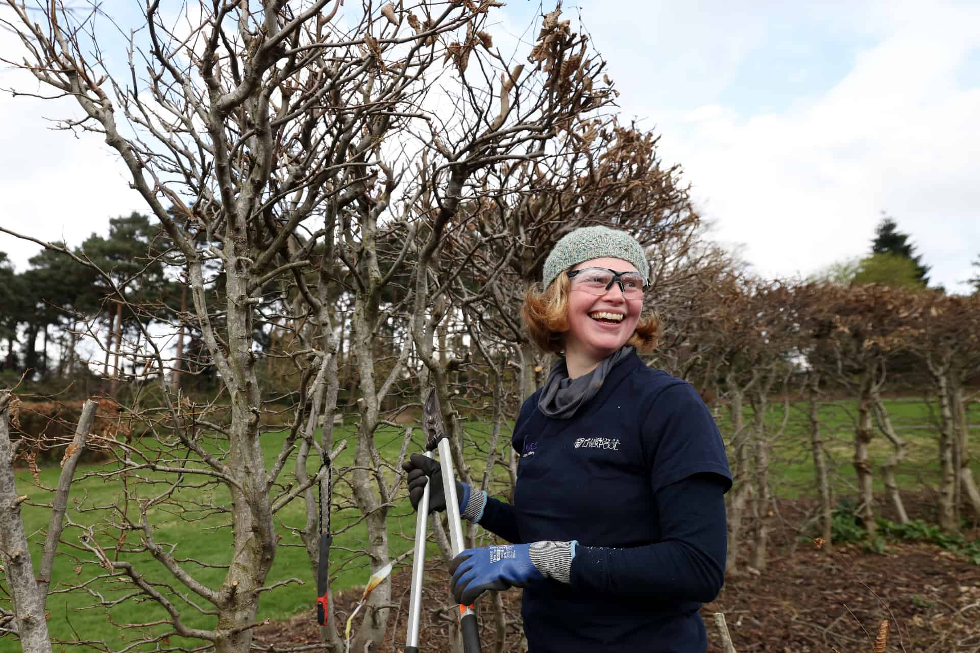 A young woman pruning trees at Ness Gardens.
