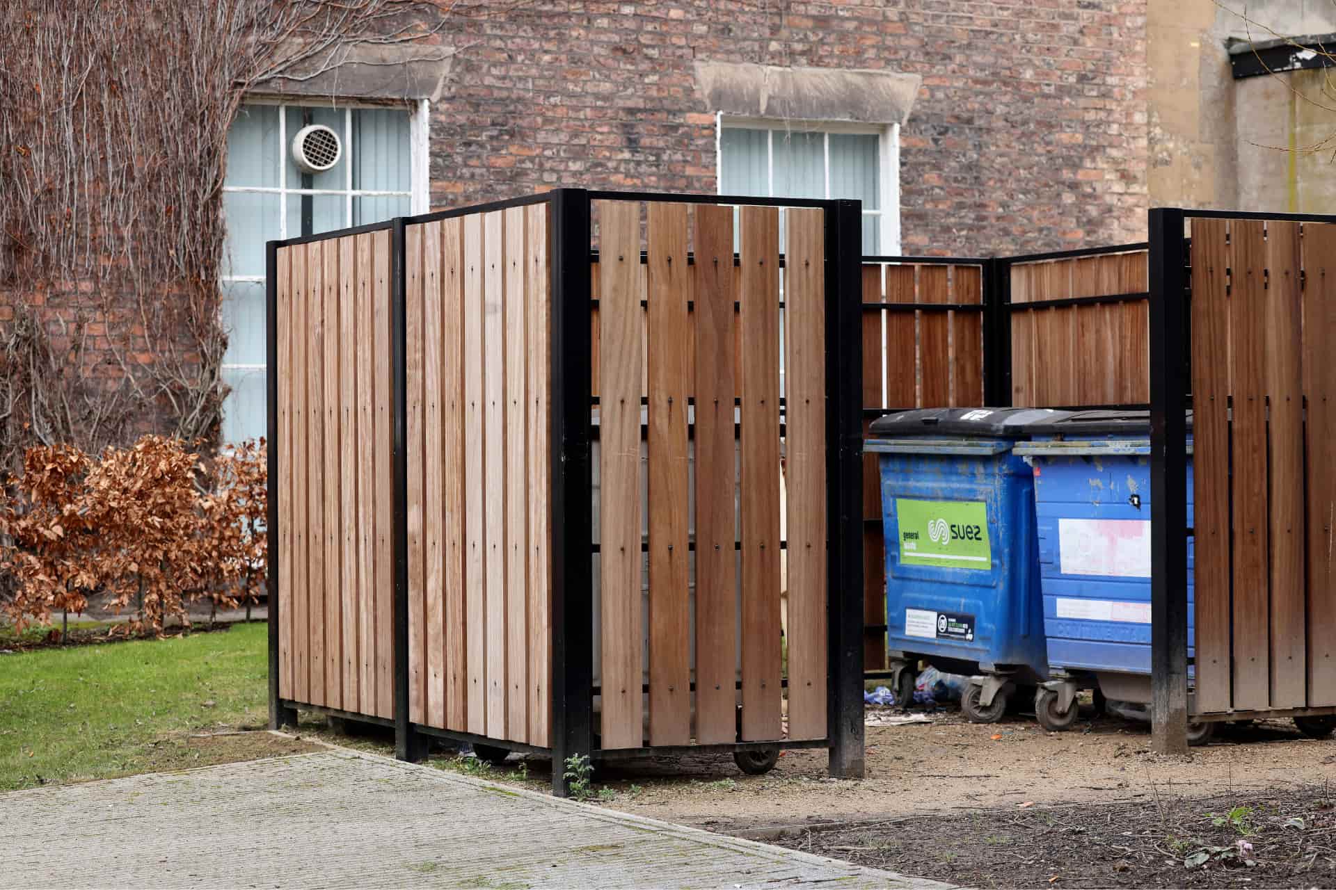 Wooden fencing containing waste bins on campus.