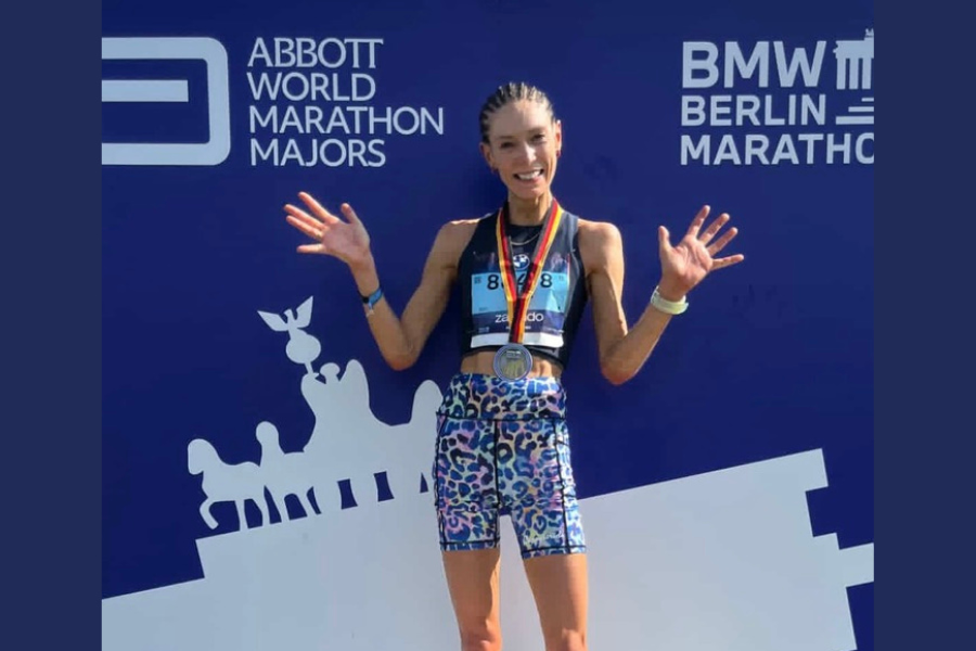 Dr Lorna Young standing on a podium celebrating having completed the Berlin marathon