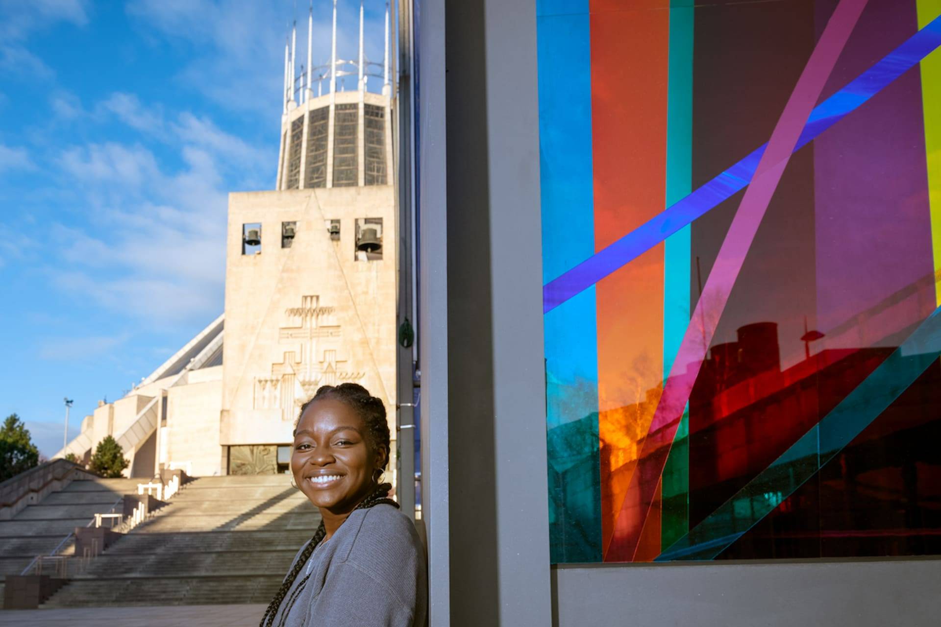 A student standing in front of the Liverpool Metropolitan Cathedral.